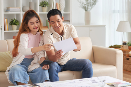 smiley couple looking at the legal loan offer from their go-to Ang Mo Kio money lender, Galaxy Credit, a legal loan company